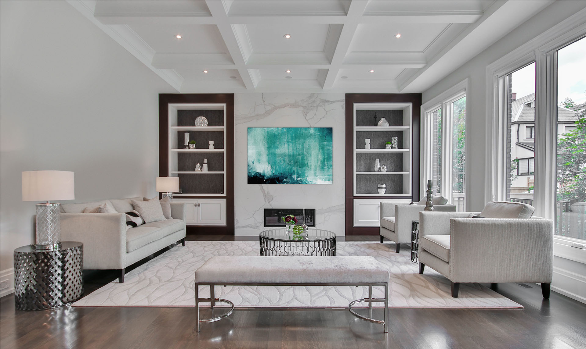 Stylized sitting room boasting hardwood floors, waffled ceiling, large windows, and a calming neutral colour scheme.